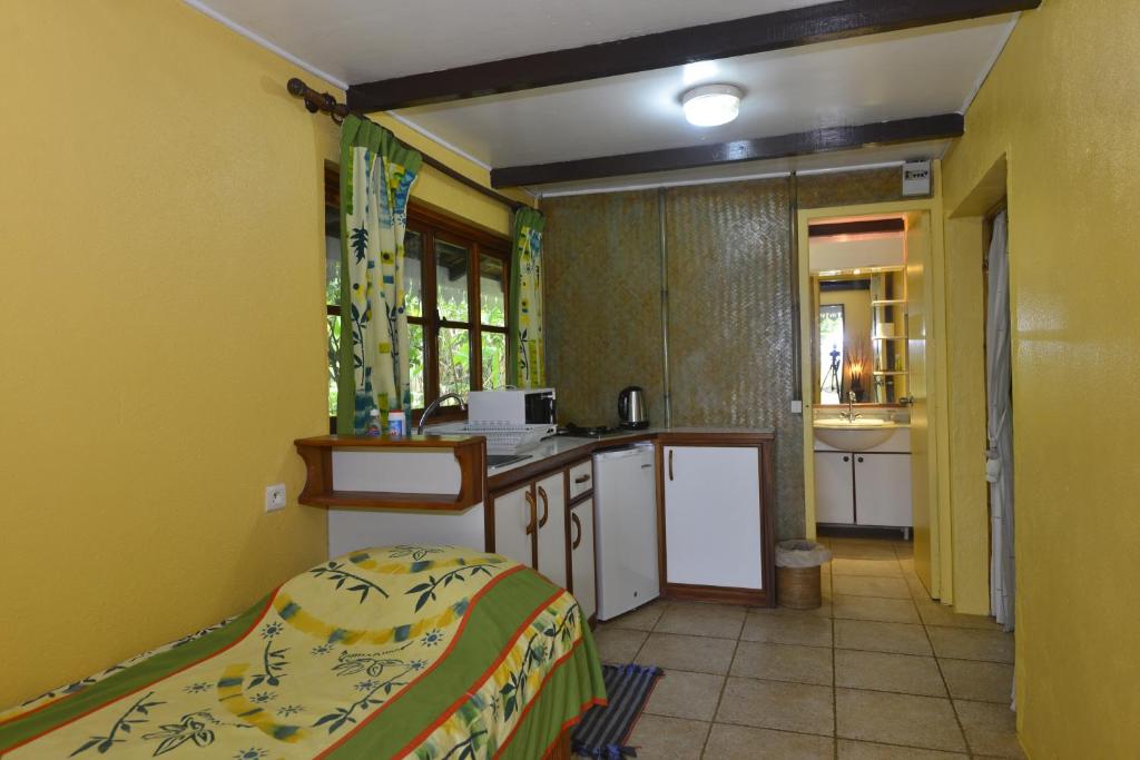 a kitchen with yellow walls and a bed in a room at Hôtel Atiapiti in Opoa