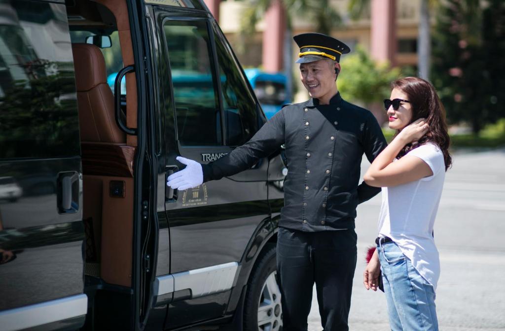 a man and a woman standing next to a van at Emperor Cruises Legacy Ha Long in Ha Long