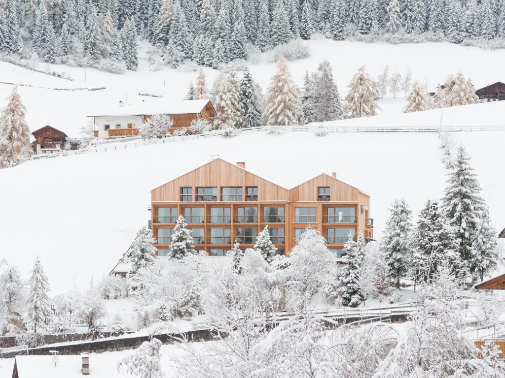 due immagini di un edificio nella neve di Hotel Tyrol a Funes