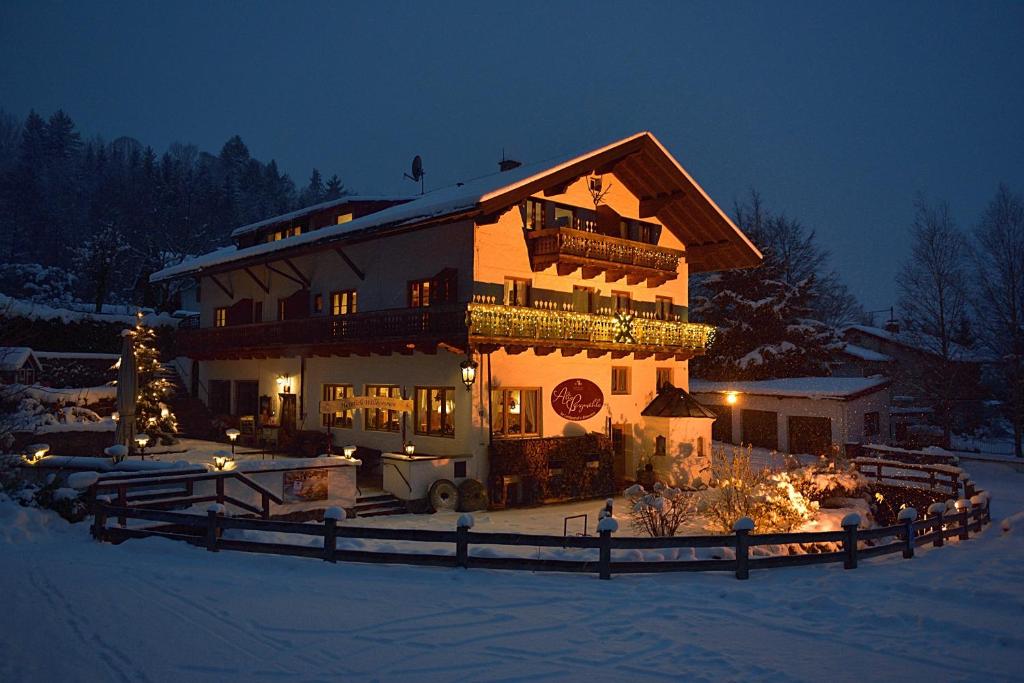 a large house with christmas lights in the snow at Gästehaus Alte Bergmühle in Fischbachau