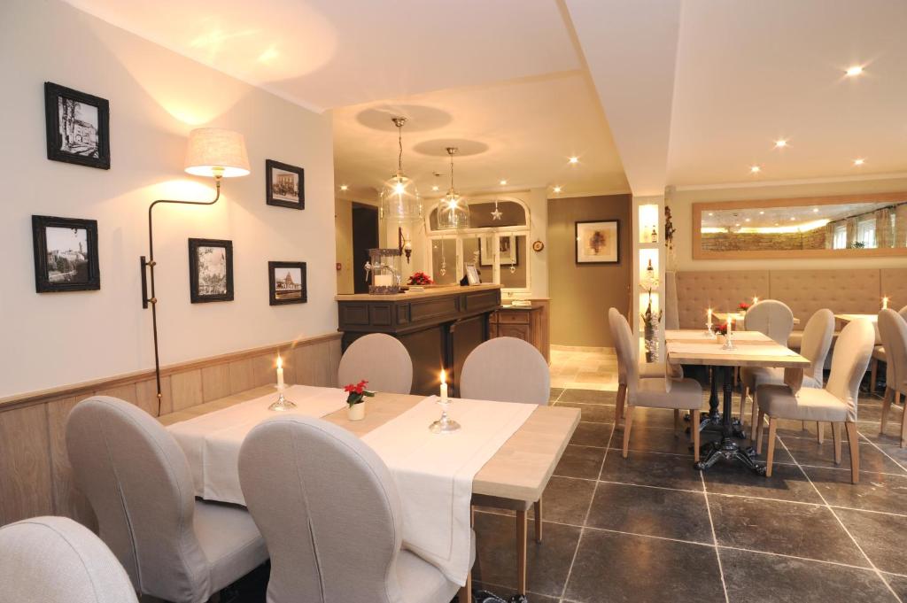 a restaurant with white tables and white chairs at Hotel Eifelland in Butgenbach