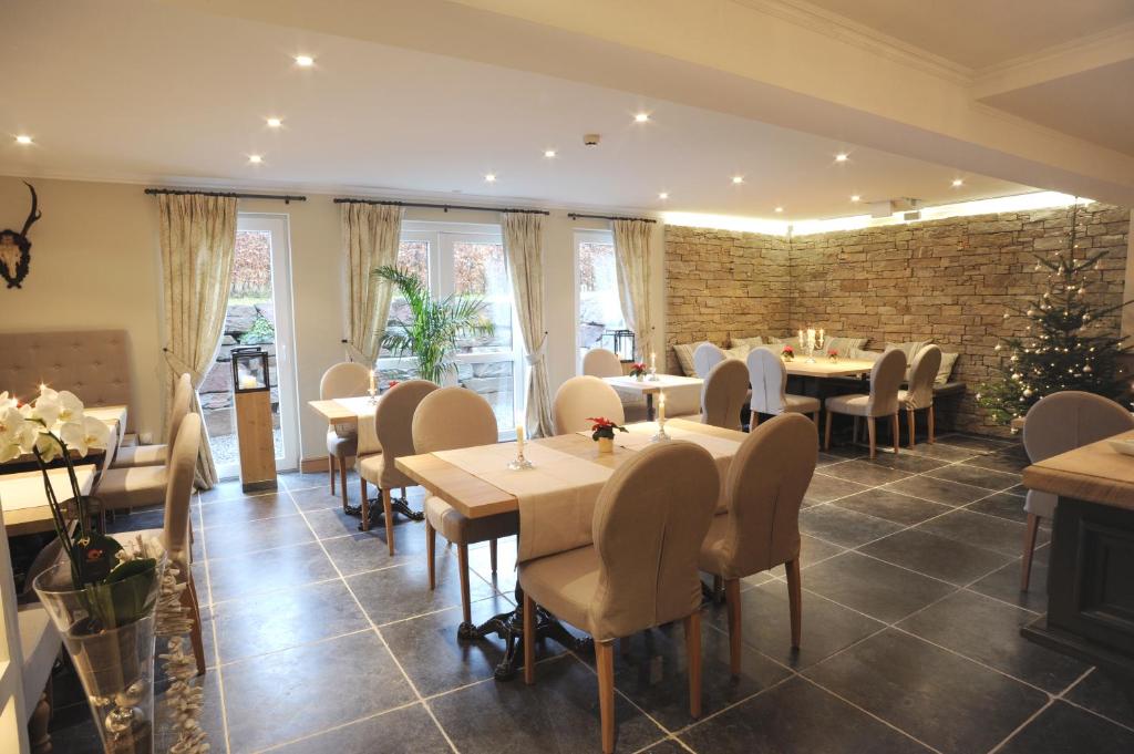 a restaurant with tables and chairs and a brick wall at Hotel Eifelland in Butgenbach