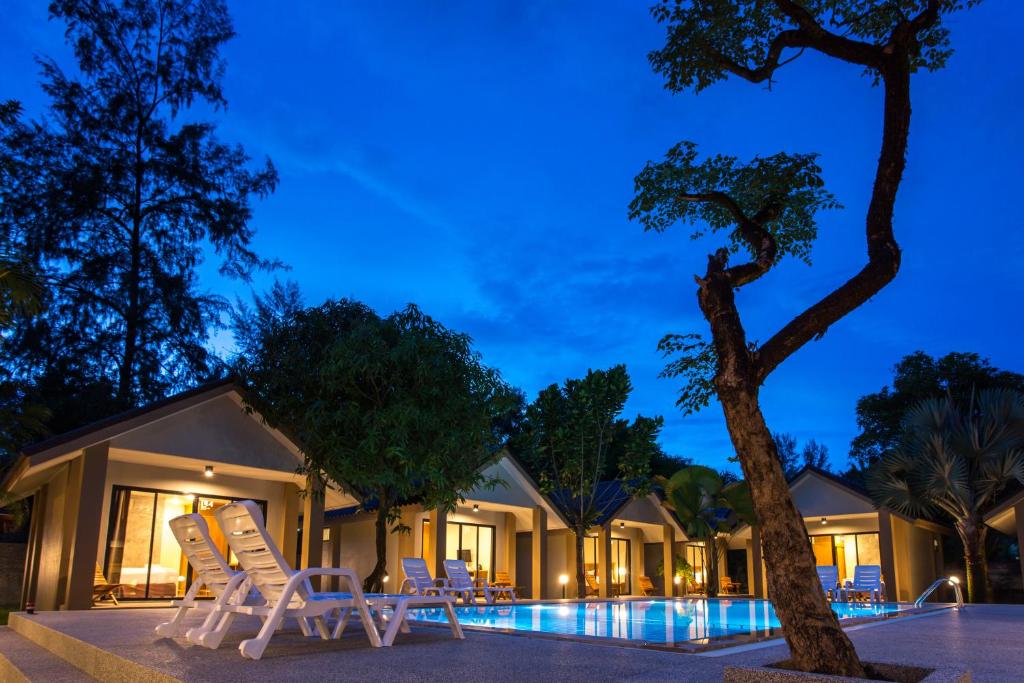 um grupo de cadeiras e uma árvore em frente a um edifício em Light Khao Lak Resort em Khao Lak