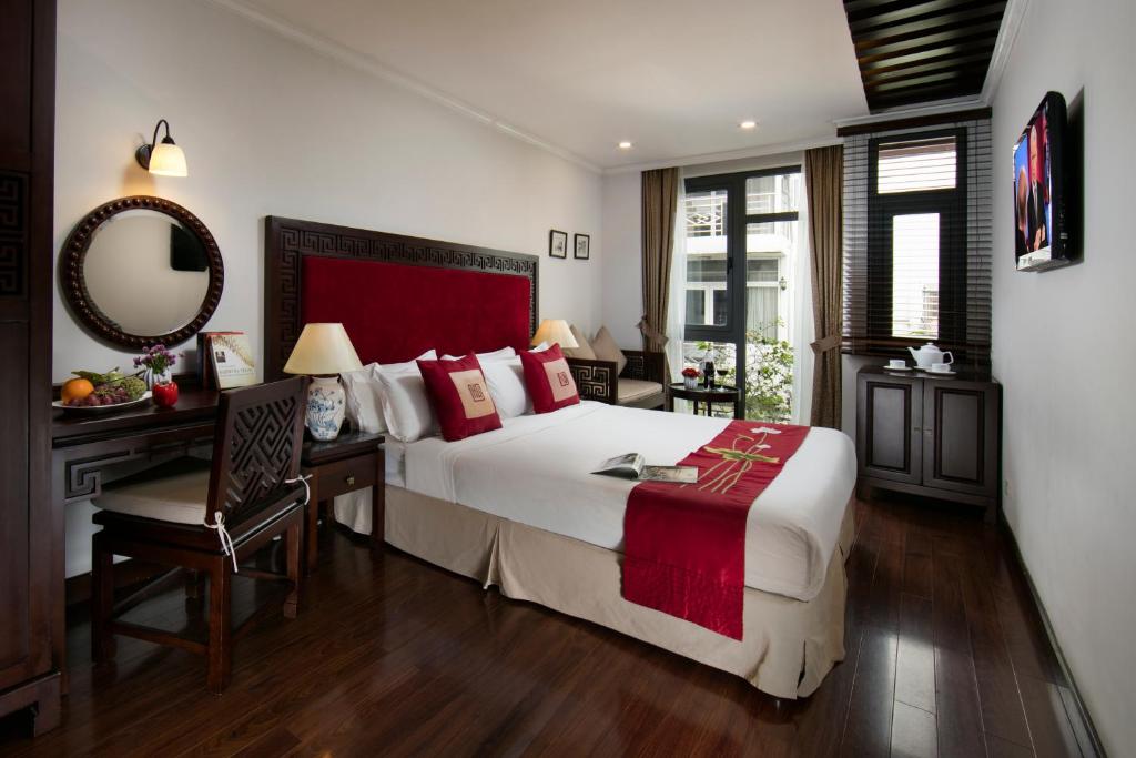 a bedroom with a bed and a desk and a mirror at Au Coeur d'Hanoi Boutique Hotel in Hanoi