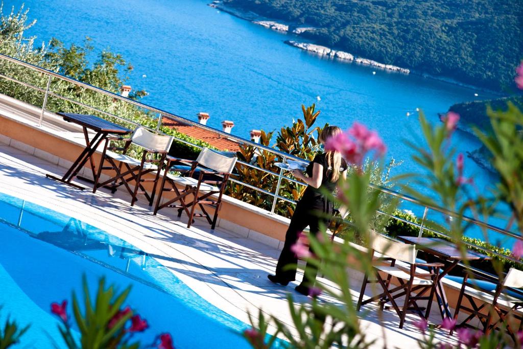 a woman taking a picture of the ocean from a hotel balcony at Hotel Villa Annette in Rabac