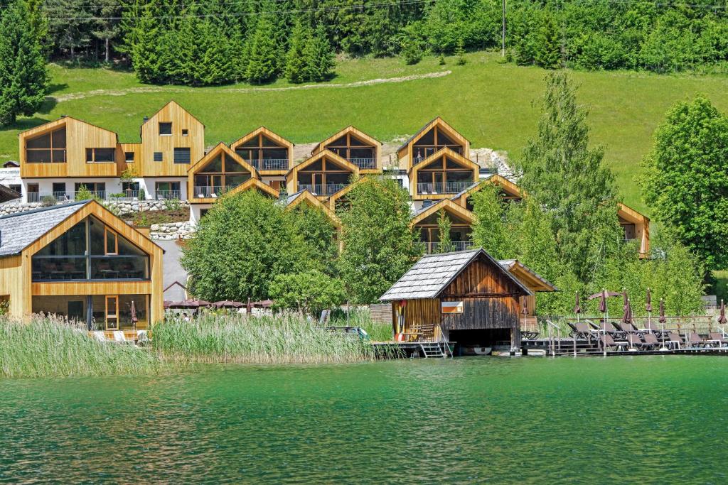 eine Gruppe von Holzhäusern neben einem See in der Unterkunft Regitnig - 4 Sterne Hotel und Chalets in Weissensee