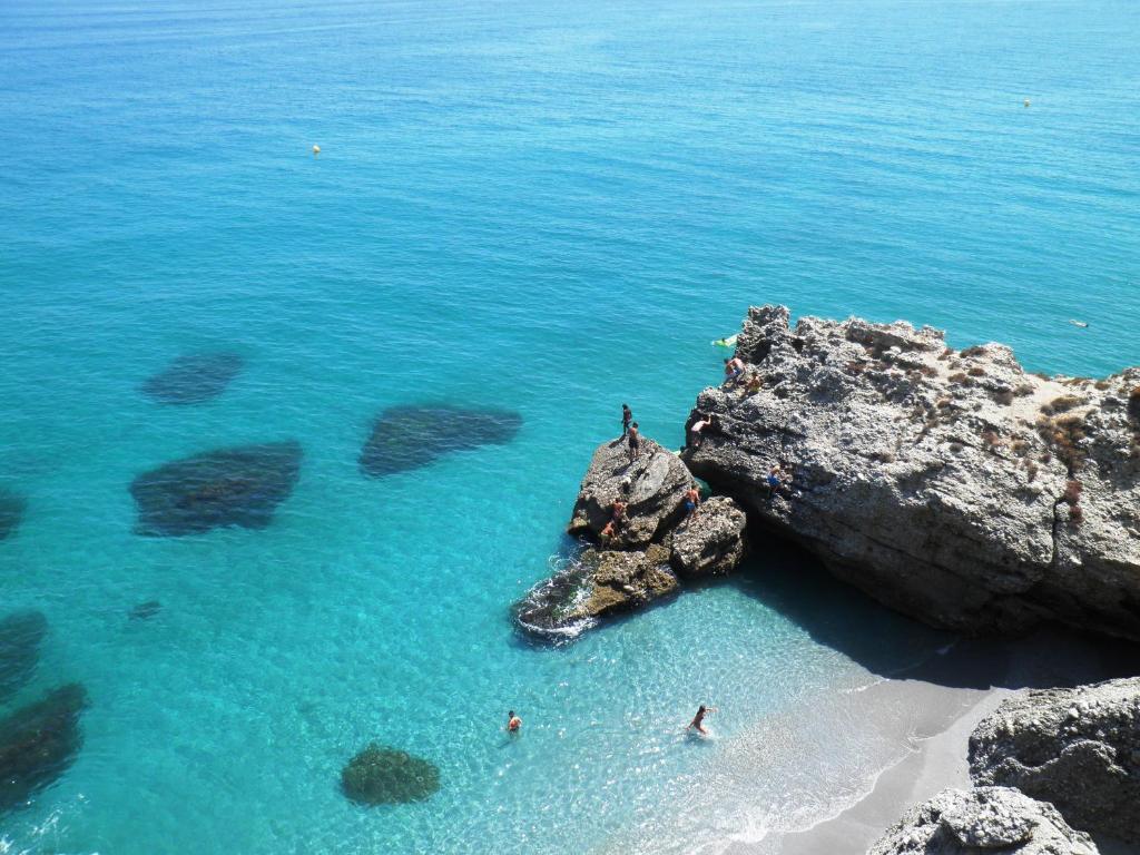 a group of people standing on a rock in the ocean at Apartamentos Eduardo Rico in Nerja