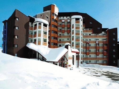 un bâtiment recouvert de neige devant un bâtiment dans l'établissement Résidence Les Mélèzes, à L'Alpe-d'Huez