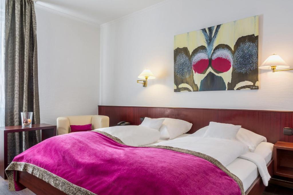 a bedroom with a bed with a purple blanket at Central Hotel in Freiburg im Breisgau