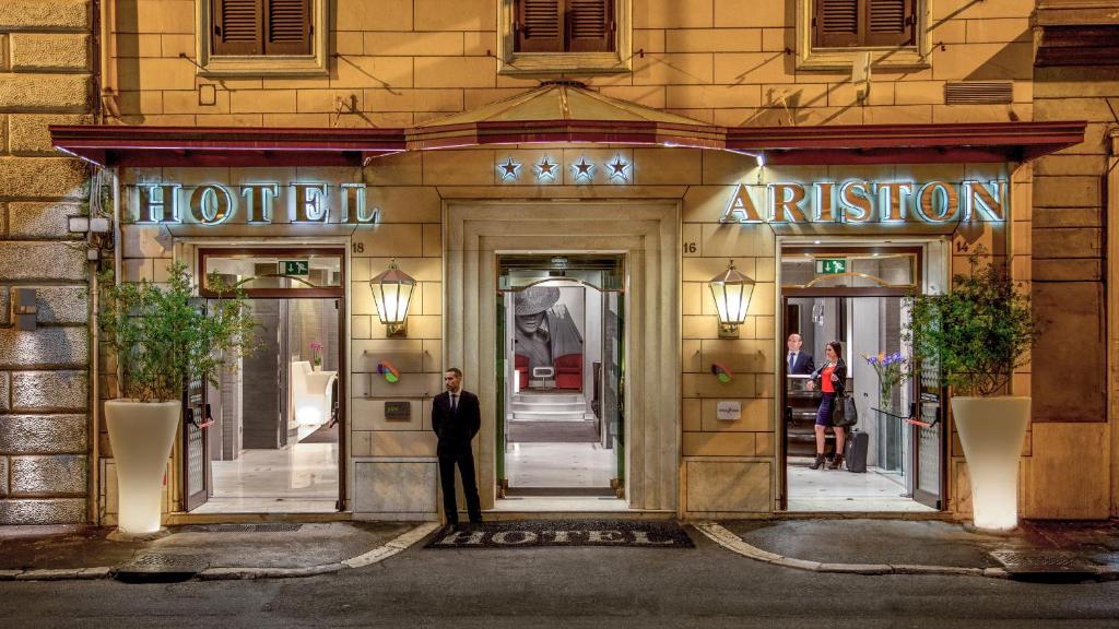 um homem parado em frente à entrada de um hotel em Hotel Ariston em Roma
