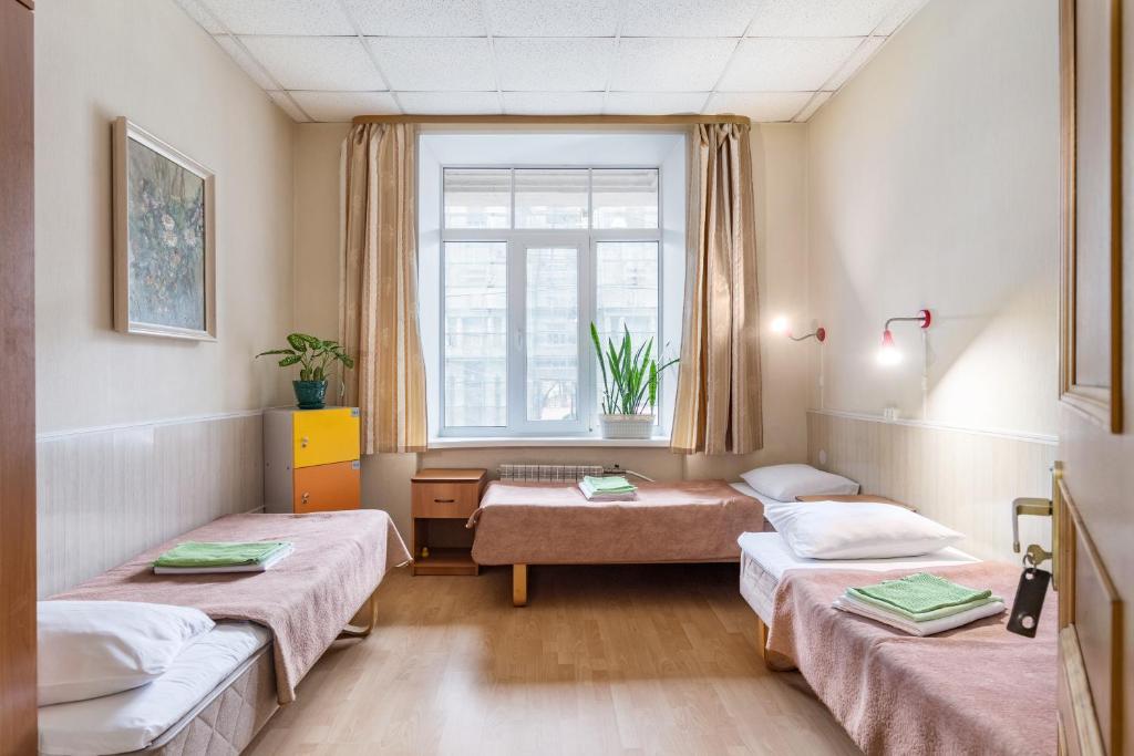 ein Krankenhauszimmer mit 3 Betten und einem Fenster in der Unterkunft Metro-Tour Hostel in Sankt Petersburg