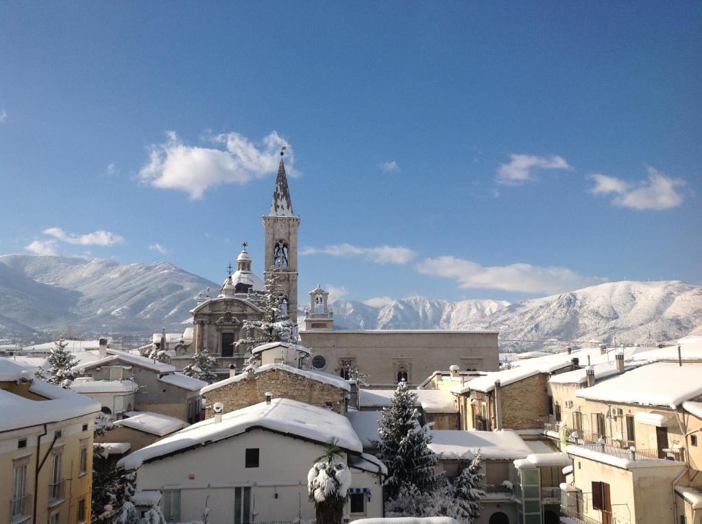 una ciudad con una torre de reloj y edificios cubiertos de nieve en La finestra Sulmò, en Sulmona