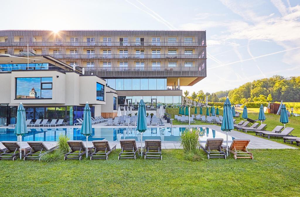 a hotel with a pool with chairs and umbrellas at LOISIUM Wine & Spa Resort Südsteiermark in Ehrenhausen