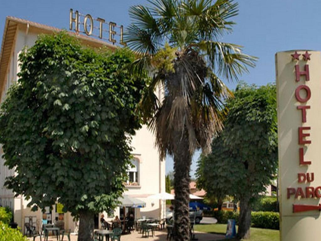 a hotel with a palm tree in front of a building at Hôtel du Parc in Salies-du-Salat