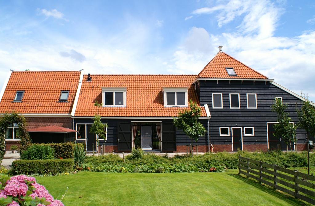 a large black house with an orange roof at Farm Overleekerhoeve in Monnickendam