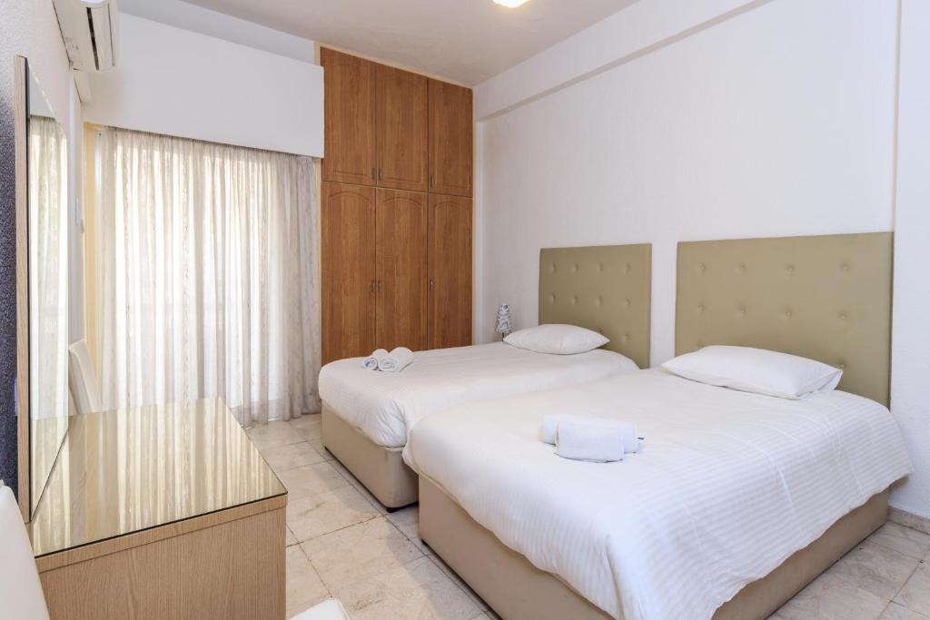 1 dormitorio con 2 camas con sábanas blancas en Les Palmiers House, en Lárnaca
