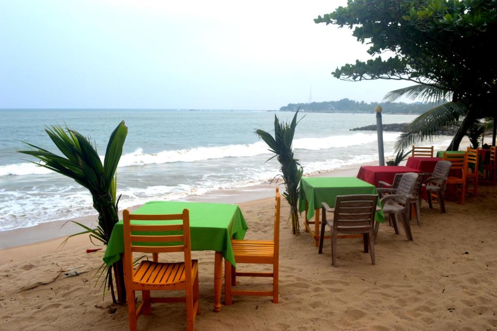 a row of tables and chairs on the beach at Dilena Beach Inn in Tangalle