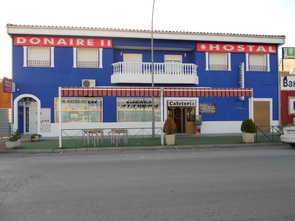 un edificio azul con mesas y sillas delante de él en Hostal Donaire II, en Tomelloso