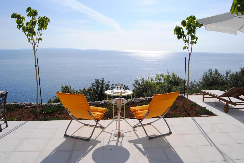 2 sillas y una mesa en un patio con vistas al océano en Leonidionhouses - The Ogra House, en Leonidio