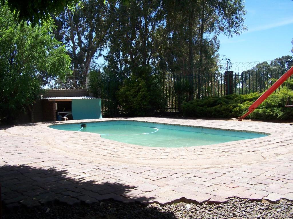 a swimming pool with a red slide in a yard at Gables Inn in Colesberg