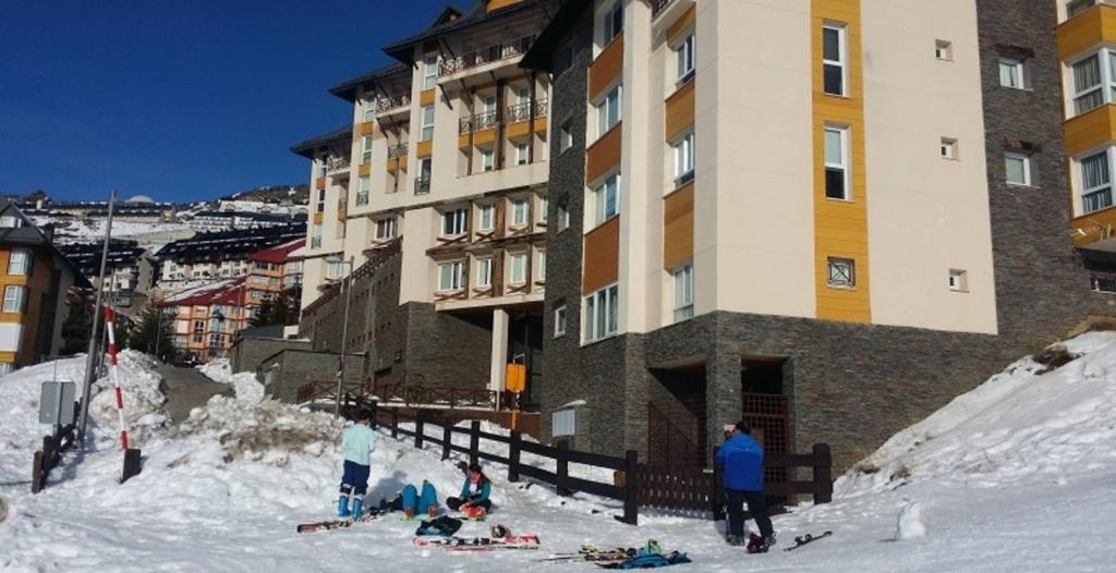 a group of people in the snow in front of a building at Apartamento Deluxe a Pie de Pista Miramar Ski in Sierra Nevada