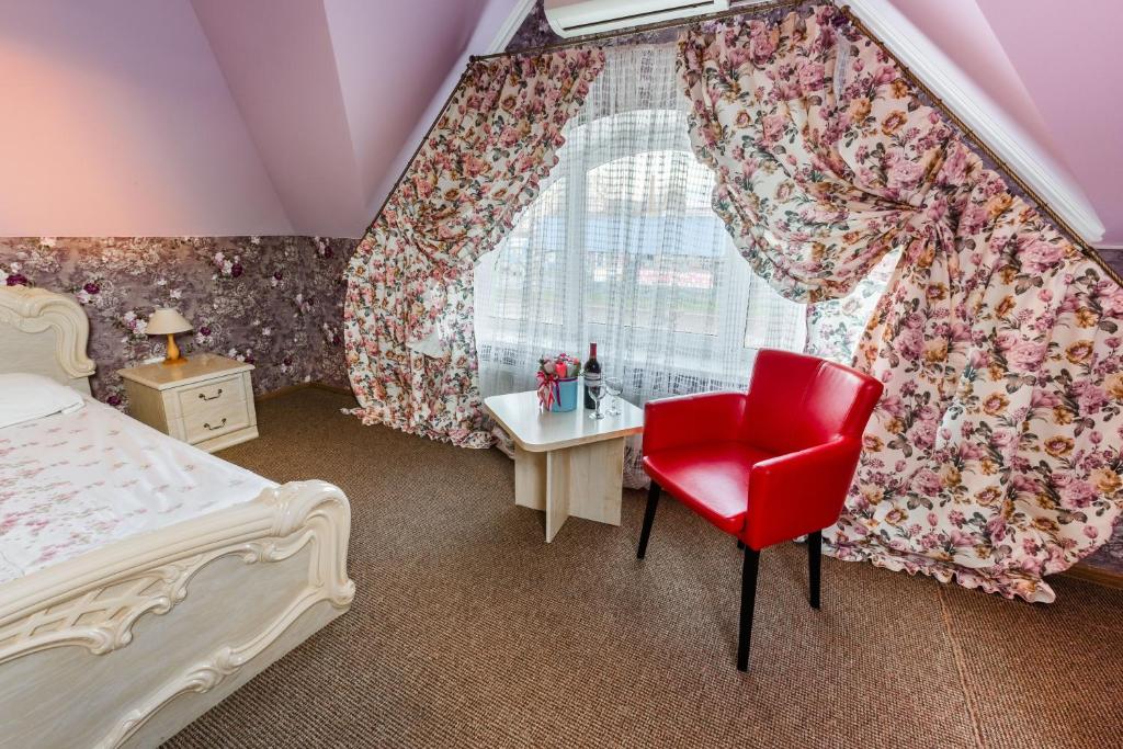 a bedroom with a red chair and a window at Everest in Ivano-Frankivsk