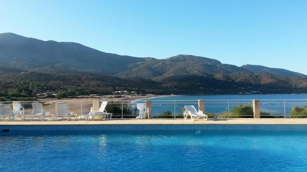 a swimming pool with chairs and a view of the water at Les Sables Blancs de la Liscia in Calcatoggio