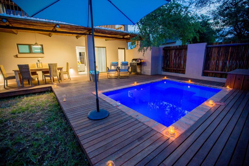 a swimming pool with an umbrella on a wooden deck at Maya Manor in Hoedspruit
