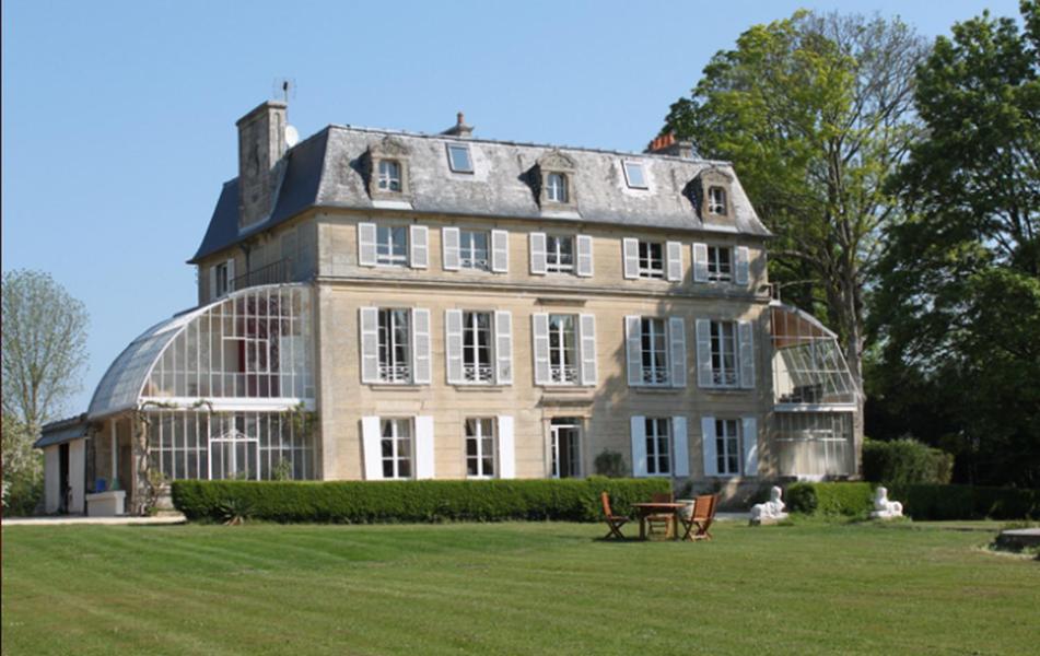 una gran casa de cristal con una mesa delante en Chambres d'Hôtes Château de Damigny, en Saint-Martin-des-Entrées