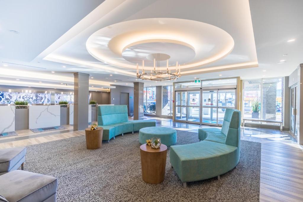 a lobby with blue chairs and a chandelier at Vittoria Hotel & Suites in Niagara Falls