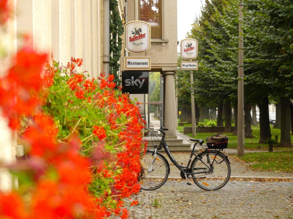 a bike parked in front of a building with flowers at Hotel zum Schwan in Nachterstedt