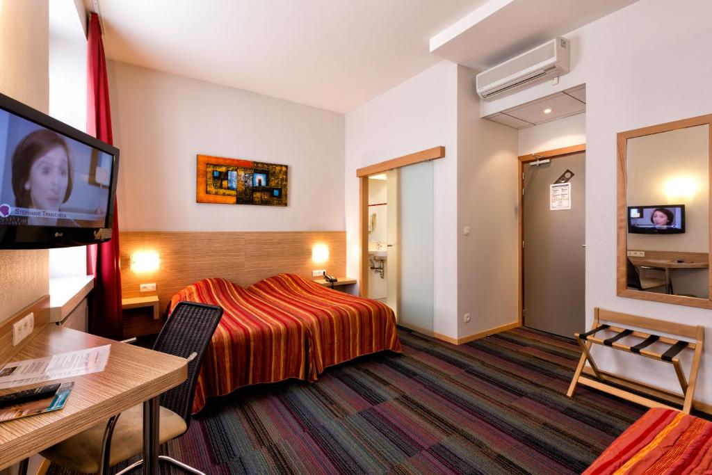 Habitación de hotel con cama y TV de pantalla plana. en Hôtel Vendôme en Estrasburgo
