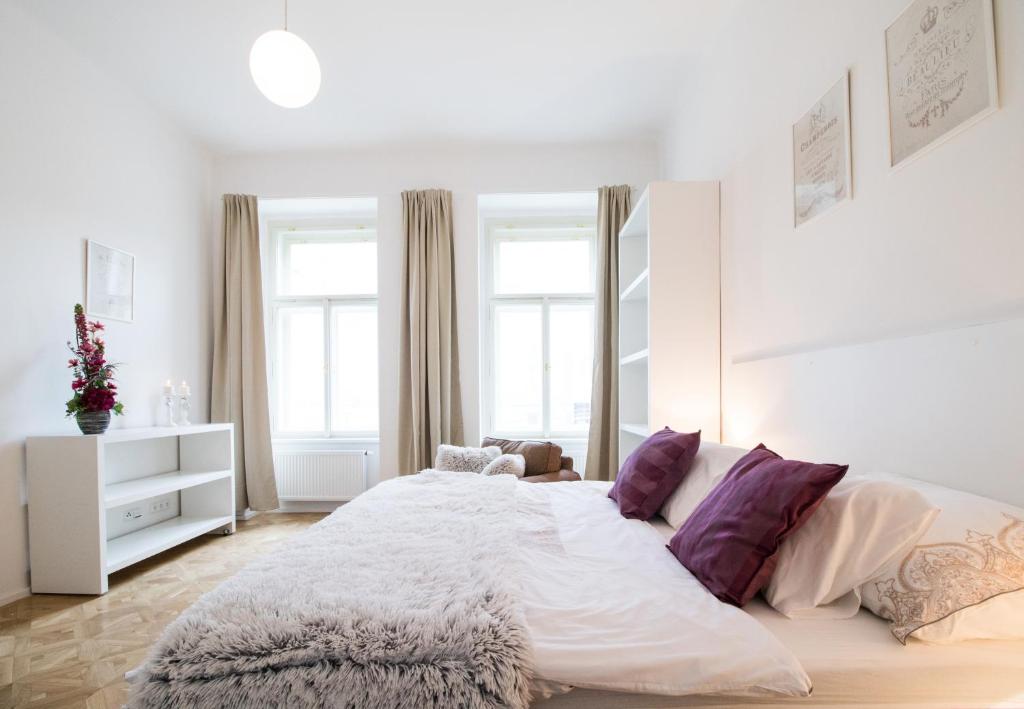 プラハにあるCosy apartment Juliaの白いベッドルーム(紫色の枕を使用した大型ベッド1台付)