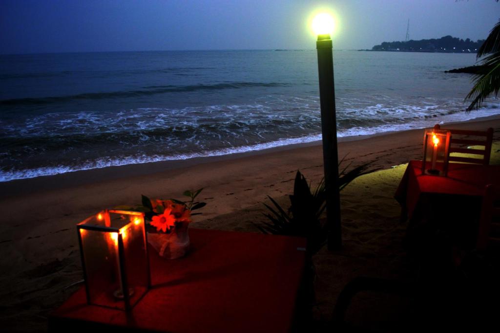 a table with candles on the beach at night at Dilena Beach Inn in Tangalle