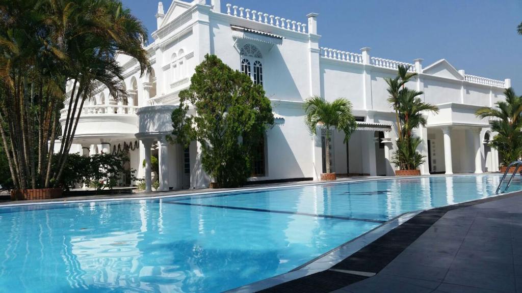 a swimming pool in front of a white building at Bougain Villa in Bentota
