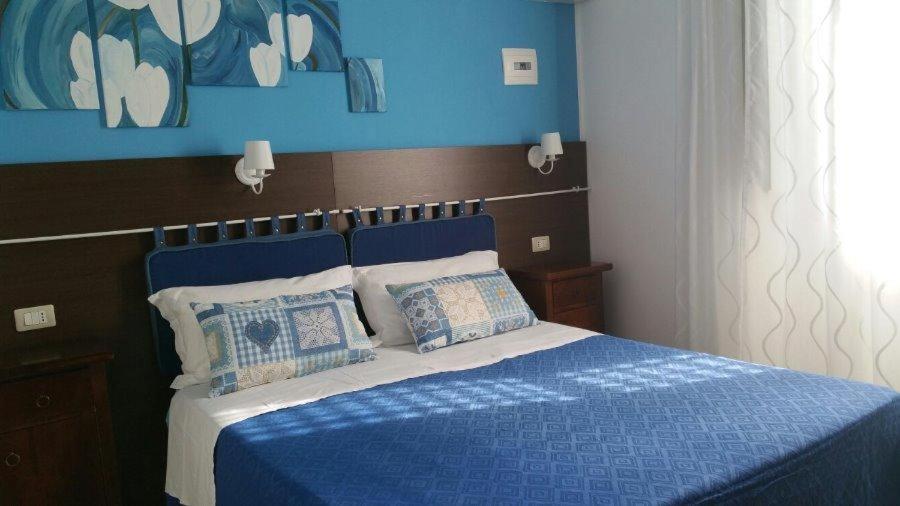een blauwe slaapkamer met een blauw bed met kussens bij Thea B&B in Acquedolci