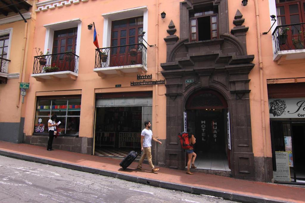 two people walking in front of a building at Hotel Huasi Continental in Quito