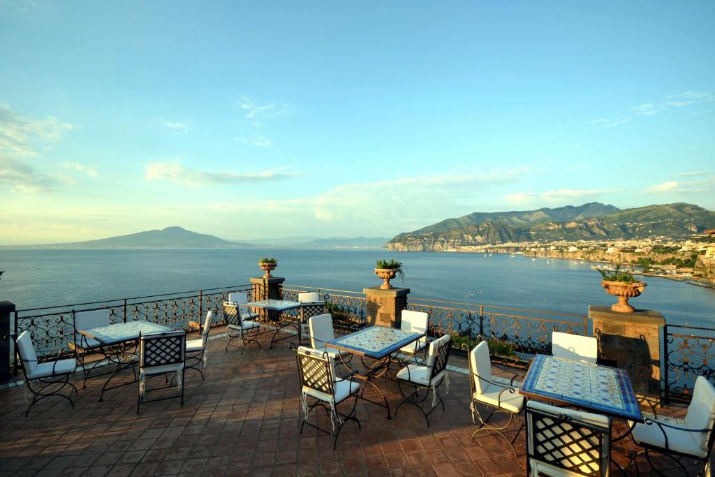 um pátio com mesas e cadeiras e vista para a água em Hotel La Tonnarella em Sorrento