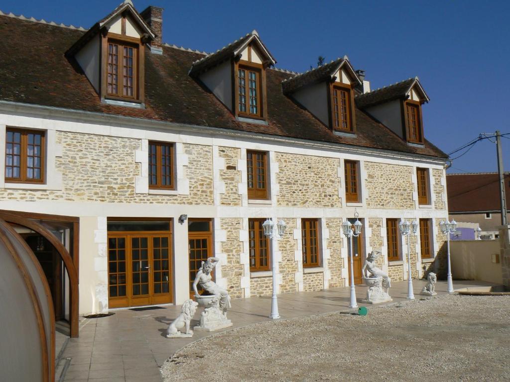 un gran edificio de ladrillo con estatuas delante en Le Manoir des Chapelles, en Venoy