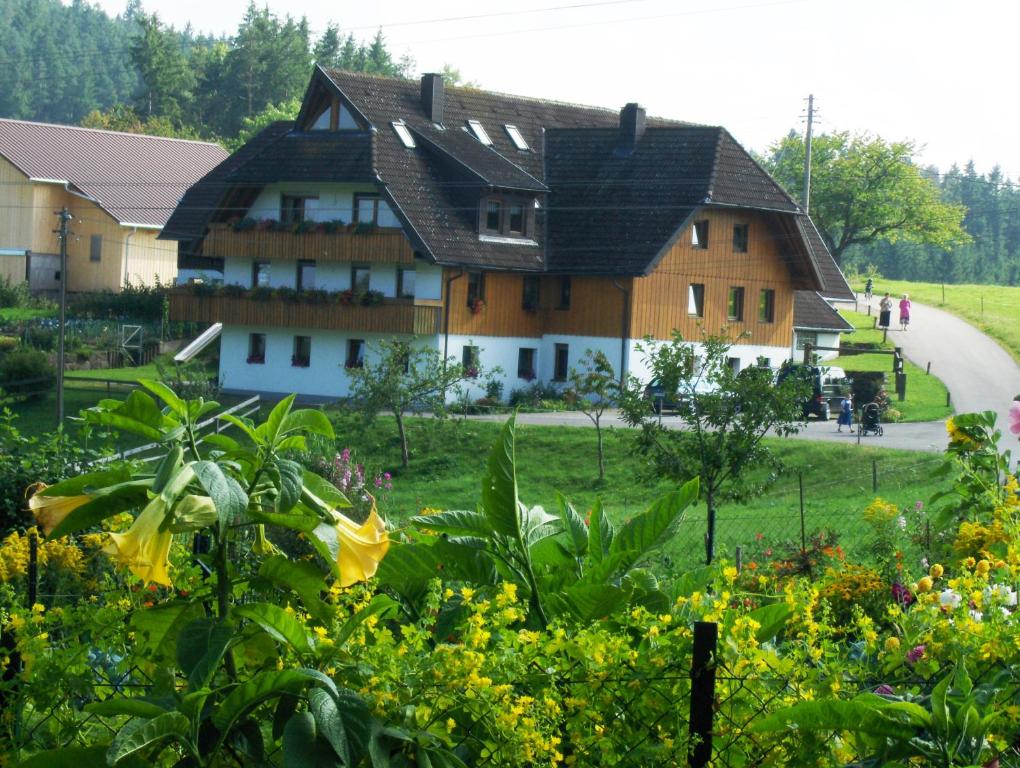 ein großes Haus inmitten eines Feldes mit Blumen in der Unterkunft Ferienbauernhof-Holops in Sankt Georgen im Schwarzwald