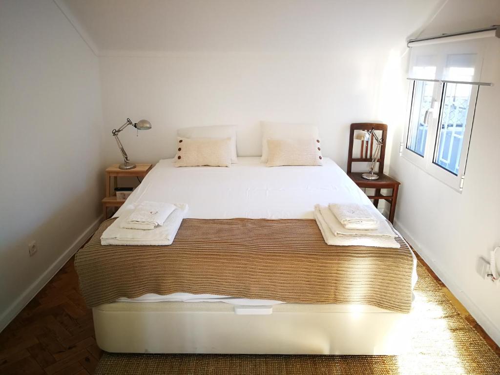 sypialnia z dużym białym łóżkiem z ręcznikami w obiekcie Cosy Attic City center w Lizbonie