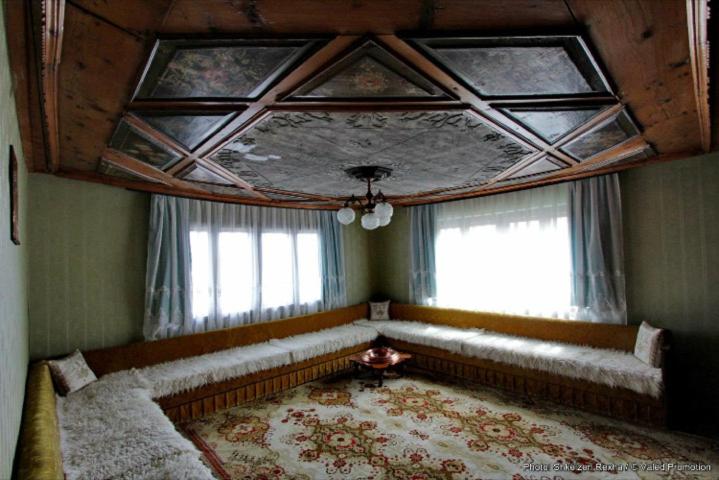 a living room with a large couch and windows at Bujtina Zhaveli in Gjakove