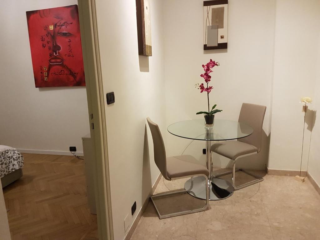 una mesa con dos sillas y un jarrón con flores. en GIURIA 35 - Elegante ed accogliente nei pressi del Valentino en Turín