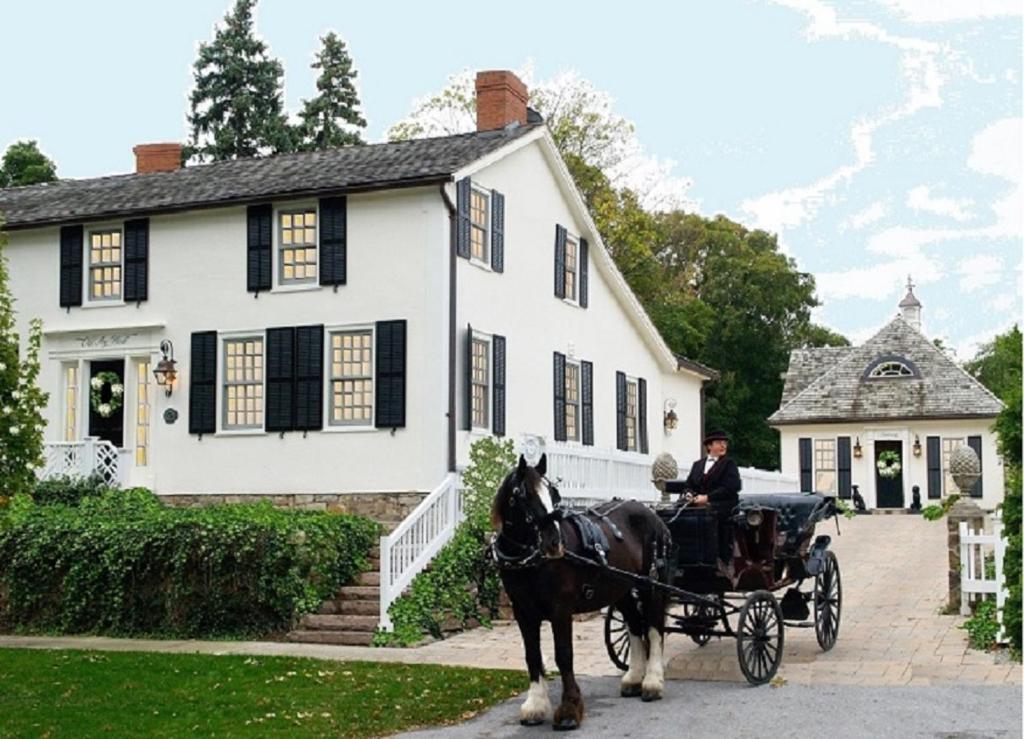 een paardenkoets voor een wit huis bij Old Ivy Walk in Niagara on the Lake