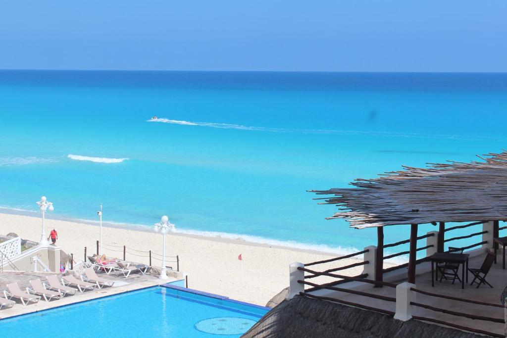 坎昆的住宿－Cancun Plaza - Best Beach，海滩旁的游泳池配有椅子和遮阳伞