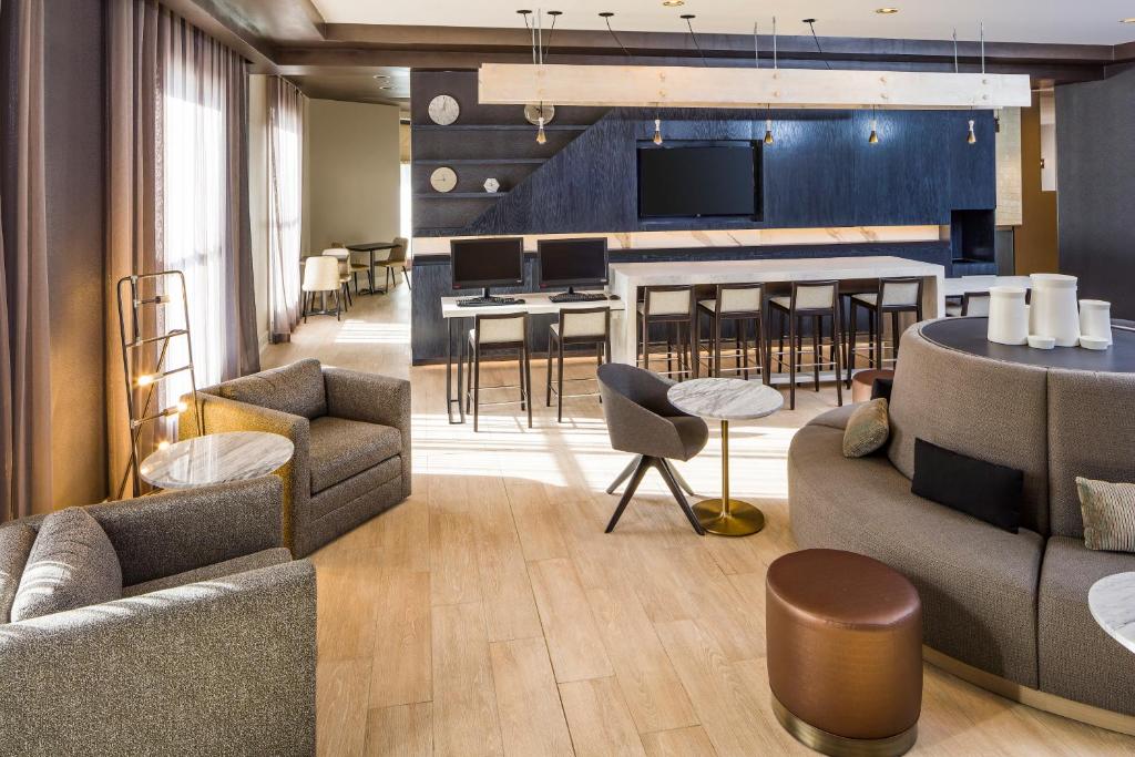 een woonkamer met banken en een bar met een tv bij DoubleTree by Hilton Boston Logan Airport Chelsea in Chelsea
