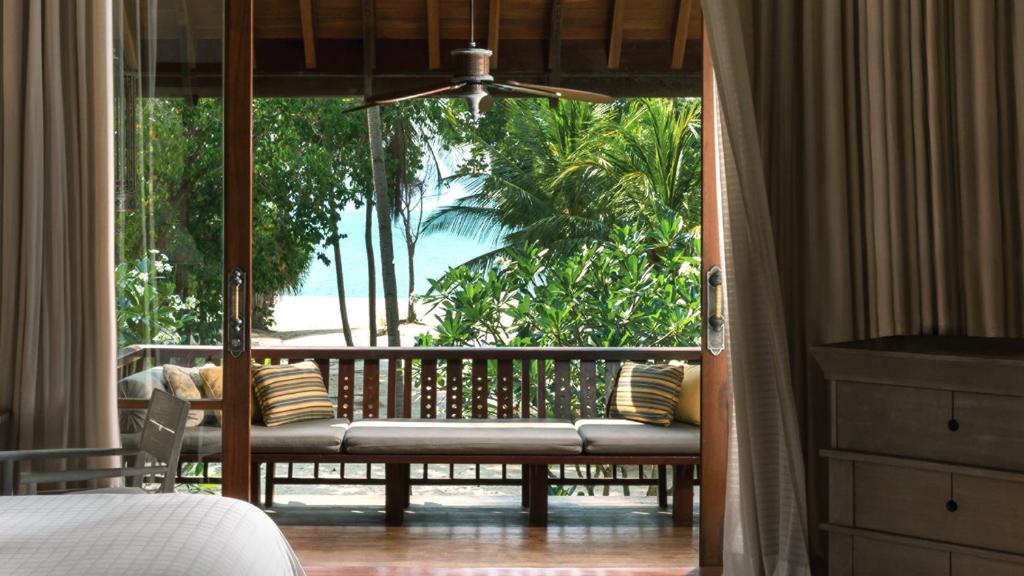 a bedroom with a balcony with a bed and a window at Four Seasons Resort Langkawi in Tanjung Rhu