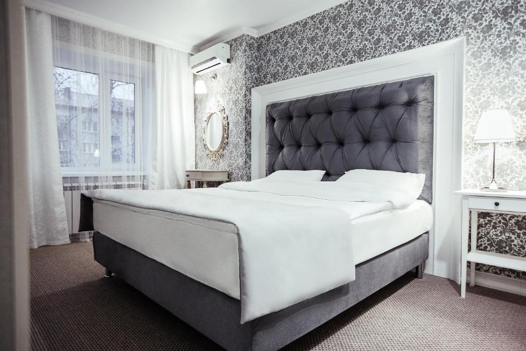 a bedroom with a large bed with a large headboard at Skif HOTEL & SPA in Petropavlovsk