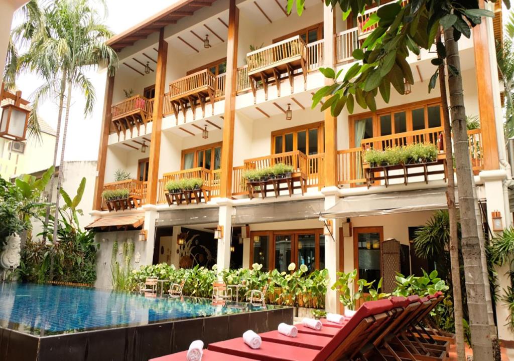 a hotel with a swimming pool in front of a building at Vieng Mantra Hotel in Chiang Mai