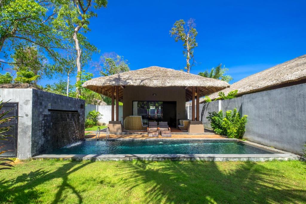a backyard with a swimming pool and a thatch roof at Beyond Khaolak in Khao Lak